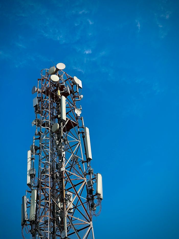 Services Close-up view of a telecommunication tower with antennas and dishes under a clear blue sky, showcasing modern infrastructure.